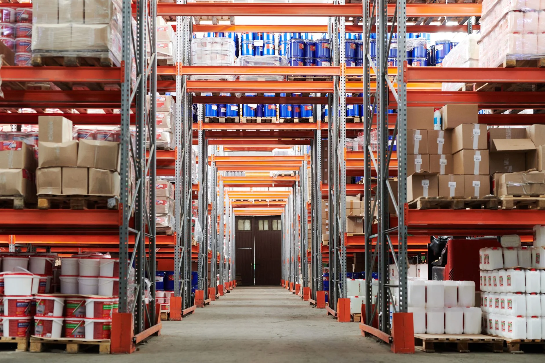 Bright warehouse interior with orange metal shelving units and stored goods.